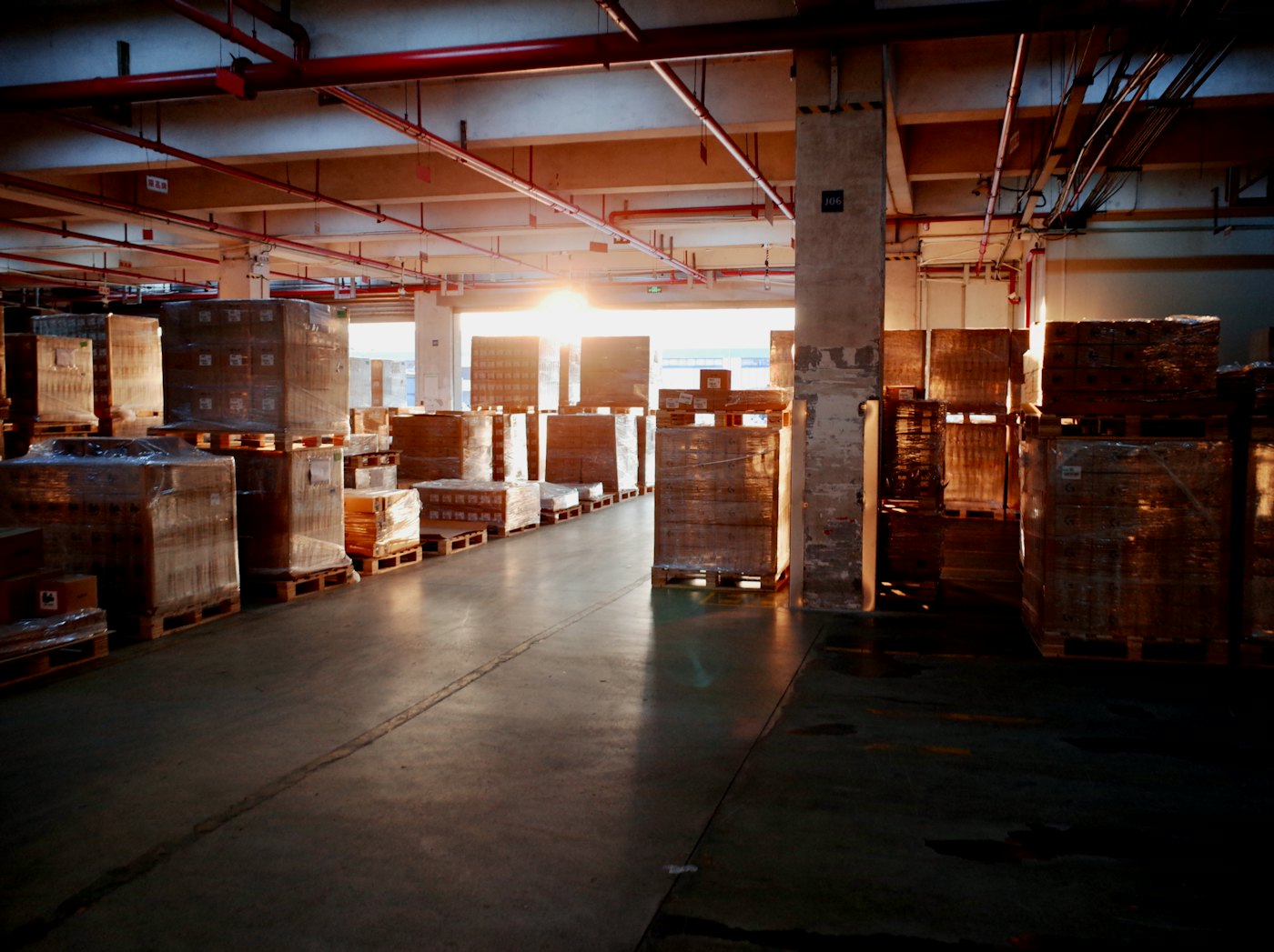 A warehouse aisle stacked with wrapped pallets